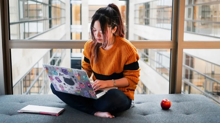 Woman sits with laptop on an office bench