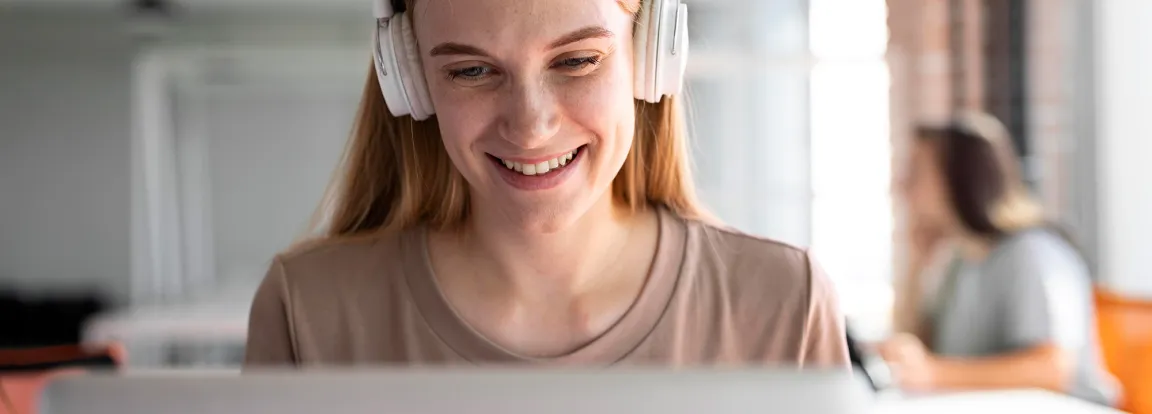 A woman wearing headphones works in a bright office space 