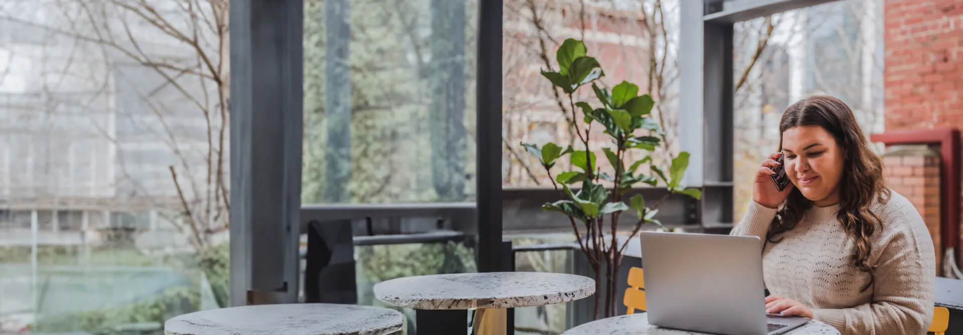 A woman takes a call on her mobile as she sits with her laptop in an empty café