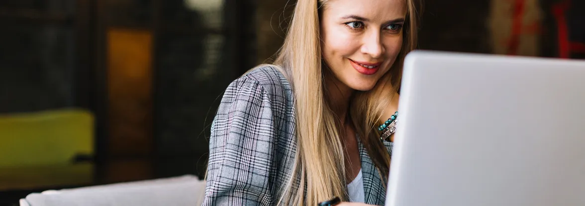 A woman smiles at her laptop