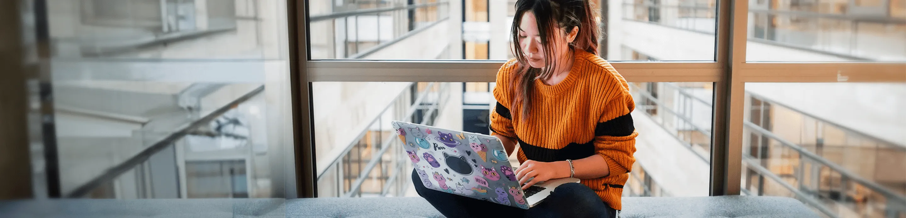 Woman sits with laptop on an office bench