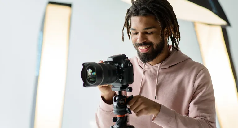 Man smiles as he sets up camera on a tripod